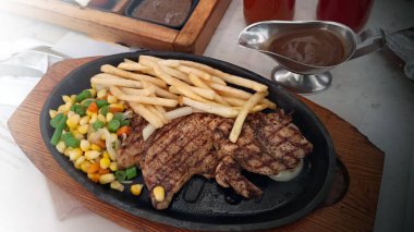 Restoran masasında servis edilen kızarmış patates ve sebzeli tavuk bifteğini kapat.