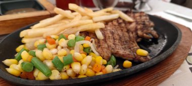 Restoran masasında servis edilen kızarmış patates ve sebzeli tavuk bifteğini kapat.