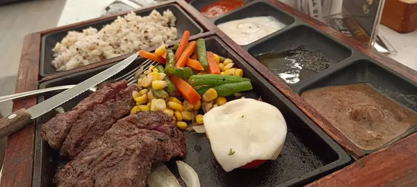 Restoran masasında servis edilen biftek, pirinç ve sebzeleri yakından izleyin.