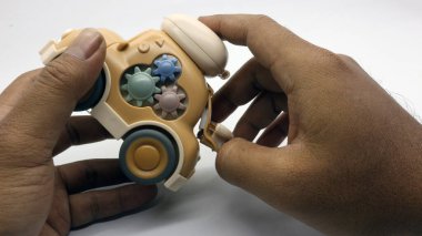 Beyaz arka planda çok şirin görünen kahverengi bir oyuncak araba..