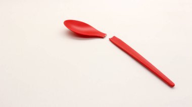 Kırık kırmızı plastik kaşık beyaz arkaplanda izole edilmiş.