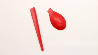 Kırık kırmızı plastik kaşık beyaz arkaplanda izole edilmiş.