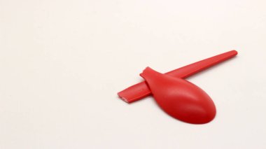 Kırık kırmızı plastik kaşık beyaz arkaplanda izole edilmiş.