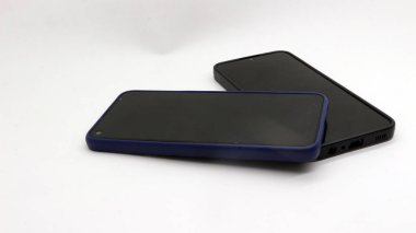 Beyaz arka planda izole edilmiş iki siyah akıllı telefon.