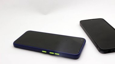 Beyaz arka planda izole edilmiş iki siyah akıllı telefon.