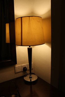 Yatağın yanında sarı ışık olan masa lambası.