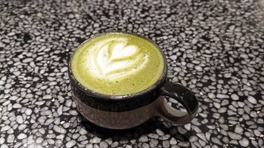 Bir fincan kibrit yeşil çay latte, mermer bir masada..