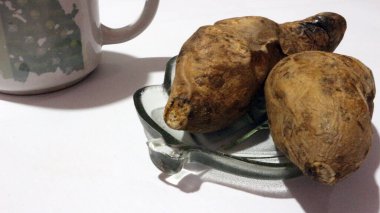 Kaynamış Cilembu tatlı patatesi, düz tabakta servis edilir, beyaz bir arka planı vardır..