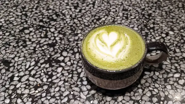 Bir fincan kibrit yeşil çay latte, mermer bir masada..
