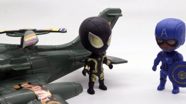 Beyaz arka planda izole edilmiş uçak oyuncağının yanındaki süper kahraman aksiyon figürü