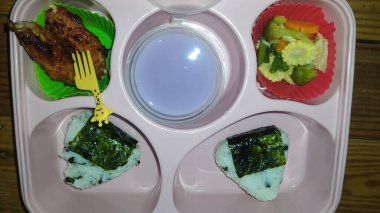 Okul çocuklarının beslenme çantası masada pirinç ve sebzelerle dolu.