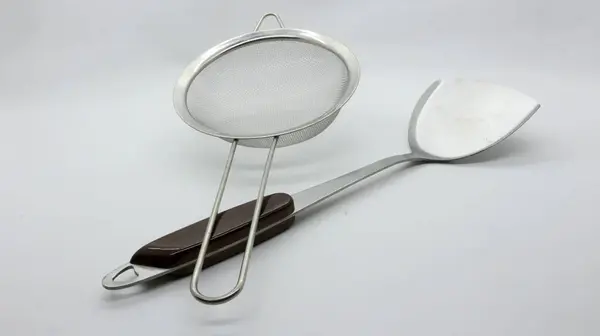 Beyaz arkaplanda paslanmaz spatula ve süzgeç izole edildi