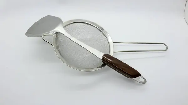 Beyaz arkaplanda paslanmaz spatula ve süzgeç izole edildi