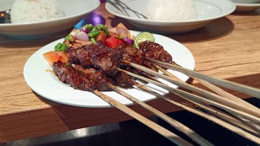 Bir tabakta servis edilen domatesli ve acılı keçi eti.