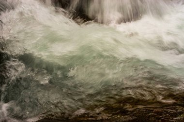 Dağdaki bir derede kayaların arasındaki suyun detaylarına, şekilleri ve renkleri ile yakından bakın.