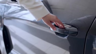 Mutlu yetişkin kadın alıcı - iş kadını - araba galerisinden yeni, modern bir elektrikli araba almaktan zevk alıyor. Pahalı satın alma, kiralama ve test sürüşü kavramı.  