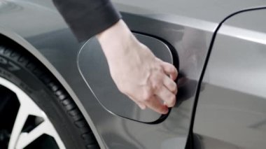 Woman hand inserts power connector into EV car. Unrecognizable person plugging in charging cable to to electric vehicle and charges batteries. Electric vehicle charging technology concept 4K