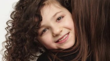 Sevecen, sevimli, evlat edinilmiş bir kız çocuğu koruyucu aileye sarılıyor gözleri kapalı bir anne, sevimli küçük bir kız çocuğu annesine sarılıyor şefkatli bir anın tadını çıkarıyor, manzarayı kapatıyor.