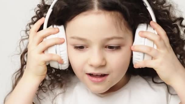 Ένα Μικρό Γοητευτικό Σγουρό Κορίτσι Ένα Γοητευτικό Χαμόγελο Ακούει Μουσική — Αρχείο Βίντεο