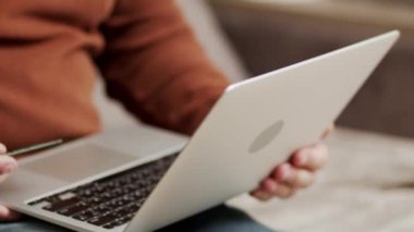 Online shopping, payment for purchases by credit card and laptop. A modern guy sitting on the couch at home uses a laptop and a bank card to pay for online purchases or deliver goods to the house.