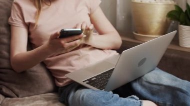 Bilgisayarlı e-bankacılık hizmetleri kullanan kadın kredi kartını elinde tutarak güvenli bir ödeme yapıyor. Kadın alıcı internet sitesine e-ticaret servisi aracılığıyla ödeme yapıyor. Evdeki kanepede oturuyor. Görüntüyü kapat