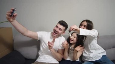 family chatting with friends or family online on mobile phone in new apartment. A young family moves into a new apartment along with the move.