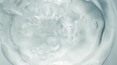 Sıvı kaplama üst görünüm. Yavaş çekimde şeffaf camlar akan köpüklü su. Hava kabarcıkları olan buzlu su girdabı.