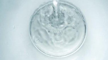 Pure Water Poured Into Glass closeup on light gray background. Super slow motion. Quenching thirst concept. Clear fresh drinking water filling glass close up