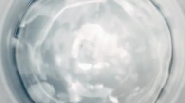 Pure Water Poured Into Glass closeup on light gray background. Super slow motion. Quenching thirst concept. Clear fresh drinking water filling glass close up