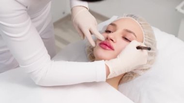 Kozmetik uzmanı hastanın yüzüne işaretler çizerek yüz hatlarını düzeltme işlemi ya da estetik ameliyatından önce. Kozmetik tedavi için hazırlık süresi.