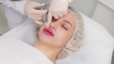 close-up, female lips. Surgeon, in medical gloves, carefully and slowly injects hyaluronic acid into woman's lips with a syringe. lip augmentation procedure. beauty injections. Plastic surgery.