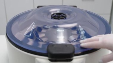 Cosmetologist extracting blood plasma using a centrifuge. The doctor takes out tubes with blood plasma.