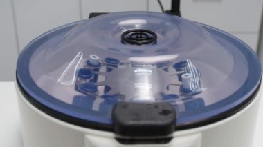 Cosmetologist extracting blood plasma using a centrifuge. The doctor takes out tubes with blood plasma.