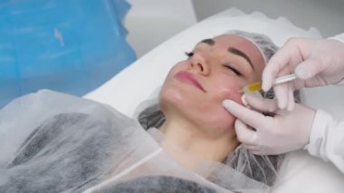 Top view medium close-up shot of platelet rich plasma face injections procedure | PRP Therapy in beauty salon | Young brown-haired female Caucasian patient.