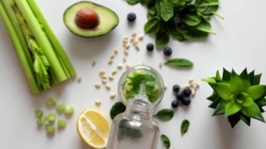 Yeşil organik sebzelerle dolu bardağa taze sıvı dökülüyor. Şeffaf karıştırıcı kasede sebzelerle akan temiz su süper yavaş çekimde. Gri arkaplanda smoothie hazırlanıyor.