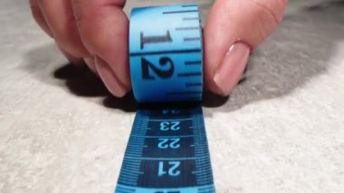 Close view of female hands using ruler and chalk for taking measurements on work-desk. Dressmaker create at home. Business at sewing studio. Tailor workshop. Seamstress create clothing details.