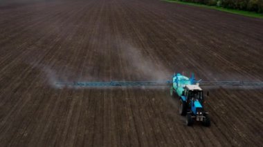Traktörün kuru ve tozlu tarım tarlalarını sürerken ve toprağı ekime hazırlarken üst görüntüsü. Tarım işi ve gıda endüstrisi konseptinin insansız hava aracı çekimi