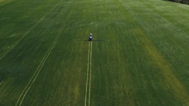 Spraying a green wheat field by tractor. The farming tractor spraying on field with sprayer, herbicides and pesticides. Industrial machine fertilizing a field. Chemicals used by agricultural tractor.