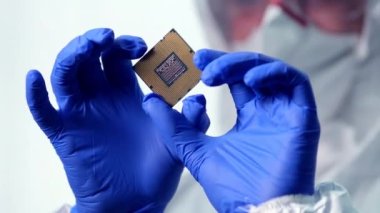 İşlemci bir teknisyenin elinde. İşlemci görünür arızalar için inceleniyor. Modern Elektronik İmalat Fabrikası Tasarım Mühendisi Mikroçipi 'nde. Yeni Nesil Mikroçipini Kapat.