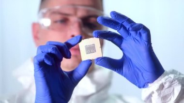 İşlemci bir teknisyenin elinde. İşlemci görünür arızalar için inceleniyor. Modern Elektronik İmalat Fabrikası Tasarım Mühendisi Mikroçipi 'nde. Yeni Nesil Mikroçipini Kapat.