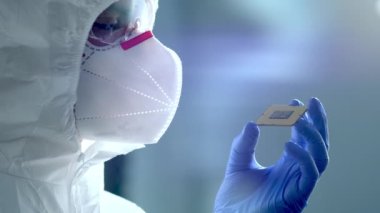 Fütürist Teknoloji Konsepti: Sterile Coverall Mühendisi Eldivenli Bilgisayar Mikroçipini Tutuyor ve İnceledi. Veri Çizgileri Suni Zeka Sembolü ile İşlemci Dijitalleştirmesi
