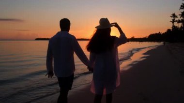 Sahilde gün batımında genç bir çift. Okyanusun arka planında, güneşin parlak ışınlarında sevgi dolu bir kadın ve erkek. Tutkulu bir adam ve aşık bir kız.