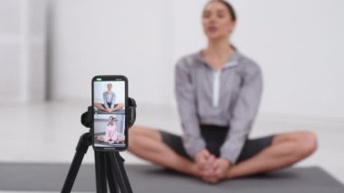 Spor salonunda yoga esneme egzersizleri yapan güçlü, güzel bir fitness kızı çevrimiçi egzersizler, antrenmanlar, akış egzersizleri için dijital tablet kullanır..