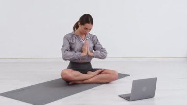 Avrupalı genç bir kadın yoga stüdyosunda mindere oturmuş video blogu kaydediyor, yoga koçu abonelerle konuşuyor ve egzersizleri anlatıyor. Spor vlog konsepti.