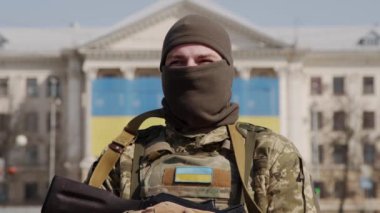 Arka planda Ukrayna bayrağı olan askeri üniformalı Ukraynalı bir askerin yakın çekimi..