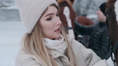 Sevimli genç mutlu kız güzel beyaz bir atın üzerinde bir ülke ranch sıvazlar. Atlar dışarıda kışın yürümek.
