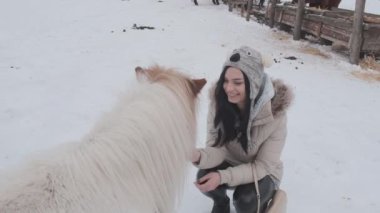 Şirin, genç, mutlu bir kız, bir çiftlik evinde güzel bir atı okşuyor. Atlar kışın dışarıda yürür..