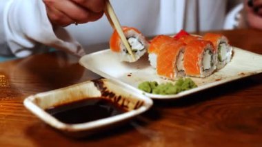 Kadının elini tutarken yakın plan çekimde suşi çubukları ve lezzetli Japon suşi ruloları al.