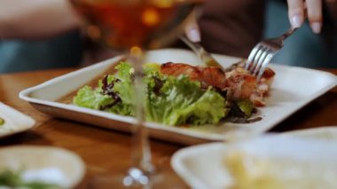 A girl cuts a steak on a plate with a fork and a knife, close-up. Dinner in a restaurant