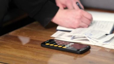 Summary and analysis of expenses and income for goods and services and salary. A person calculates utility bills and receipts using a smartphone calculator. A man counts money in cash dollars, euros.